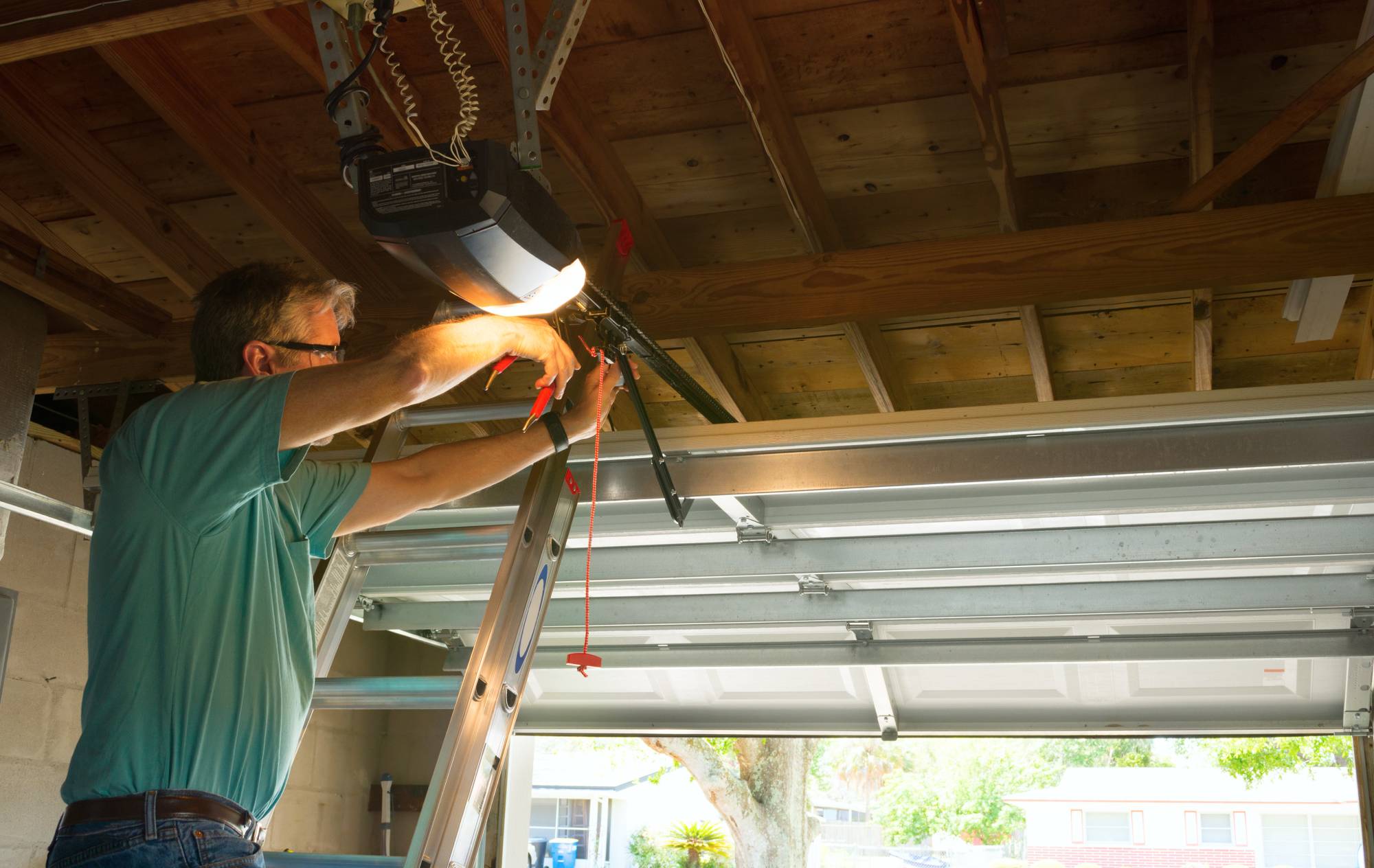 Homeowner lubricating garage door hinges and rollers during maintenance